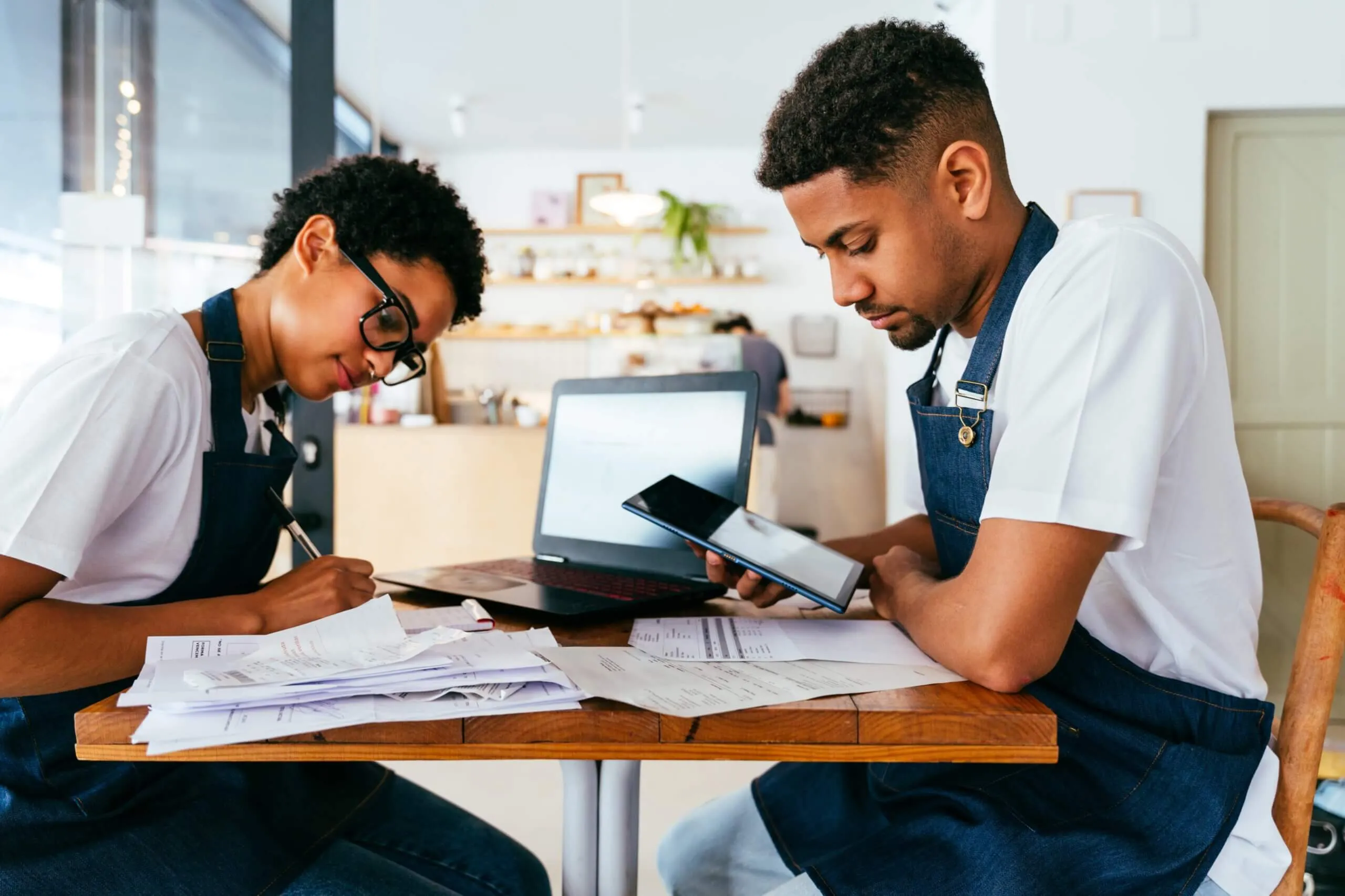 Two individuals seated at a table, reviewing business reports and paperwork together