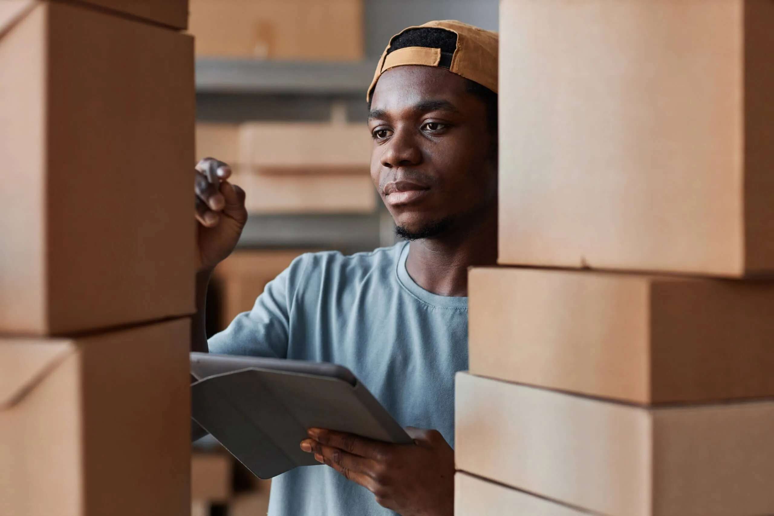  A man wearing a hat reviews a table, focused on inventory tasks 