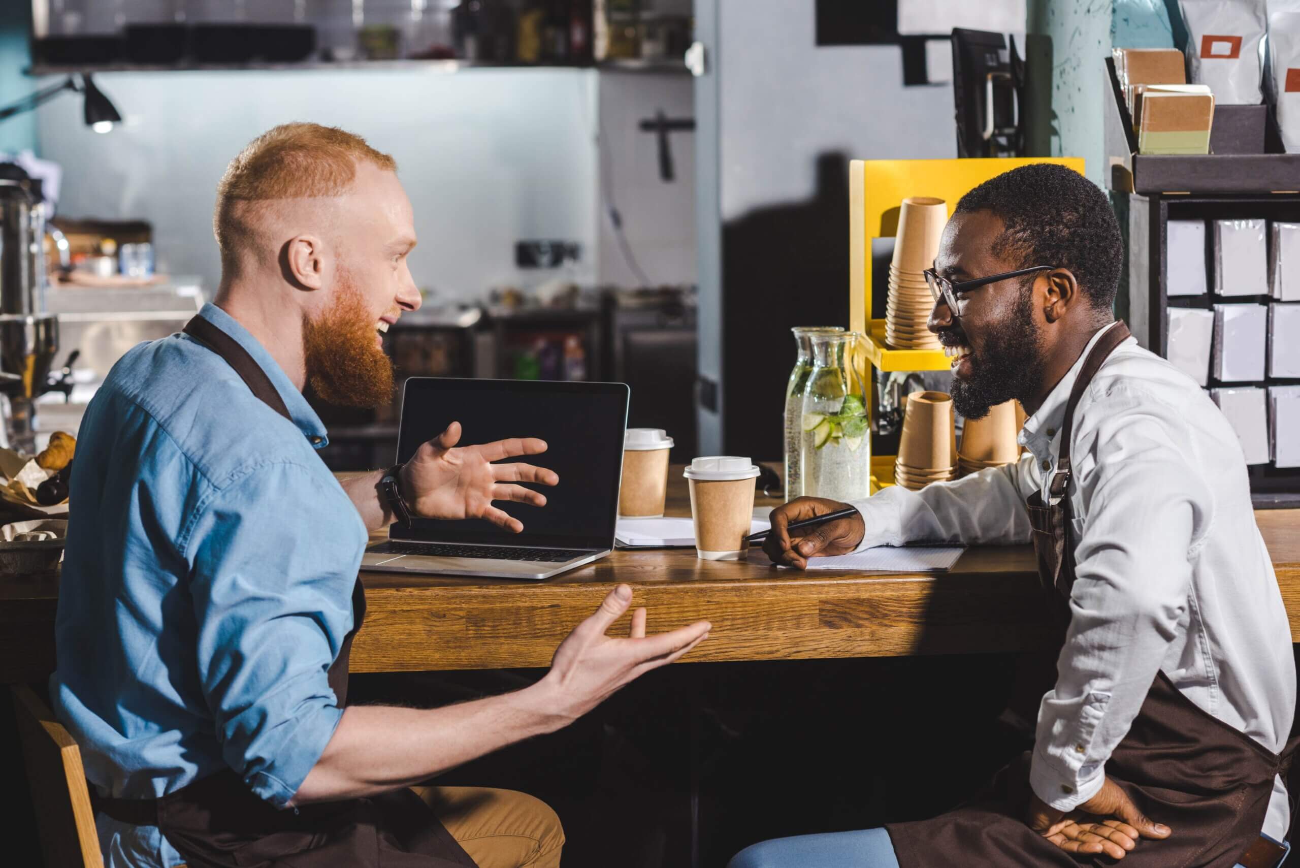 Two men sitting at a table, actively talking to each other, fostering dialogue and connection in a casual atmosphere