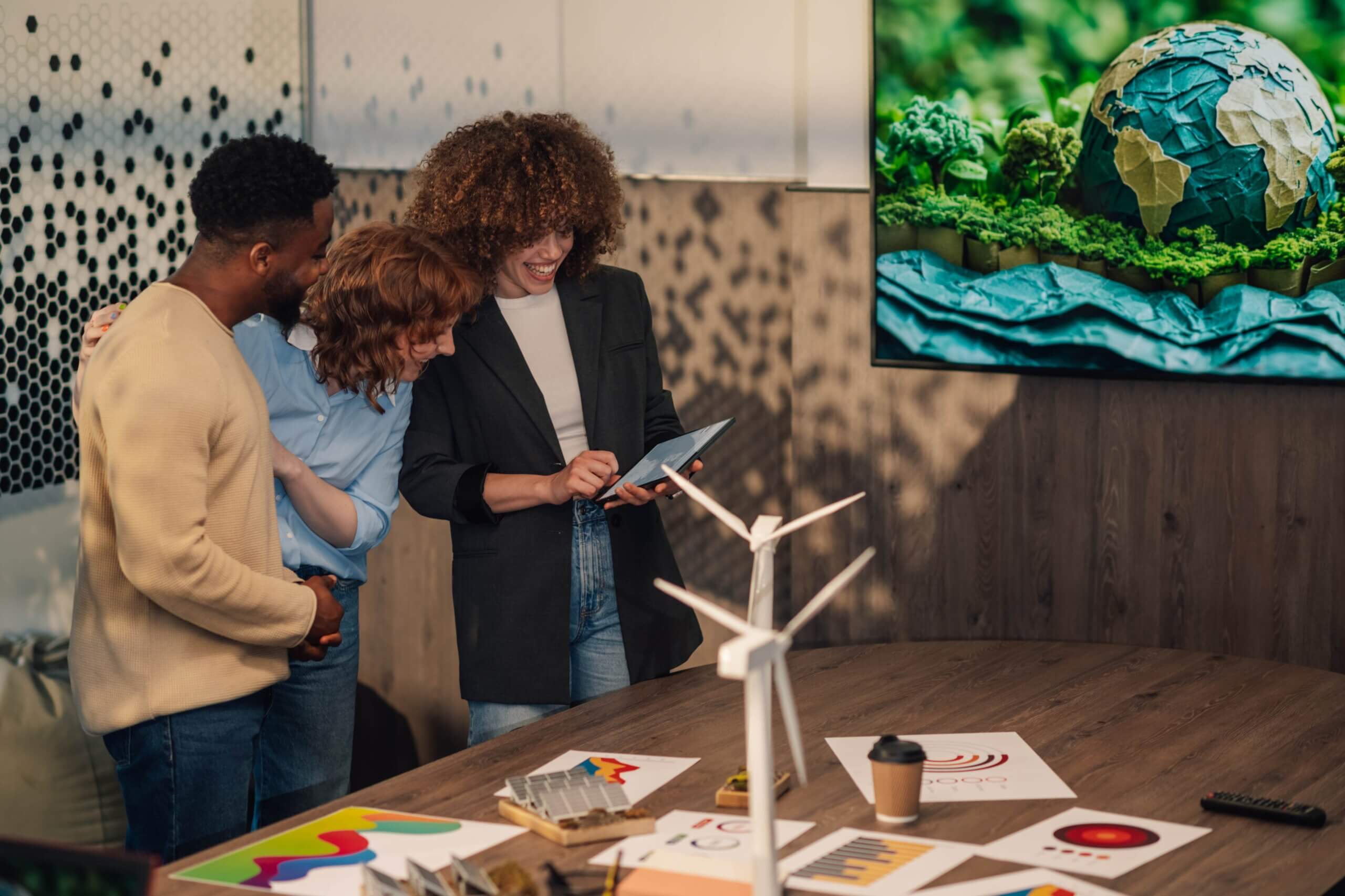 Three individuals observe a screen displaying a globe, discussing small business trends and global market insights