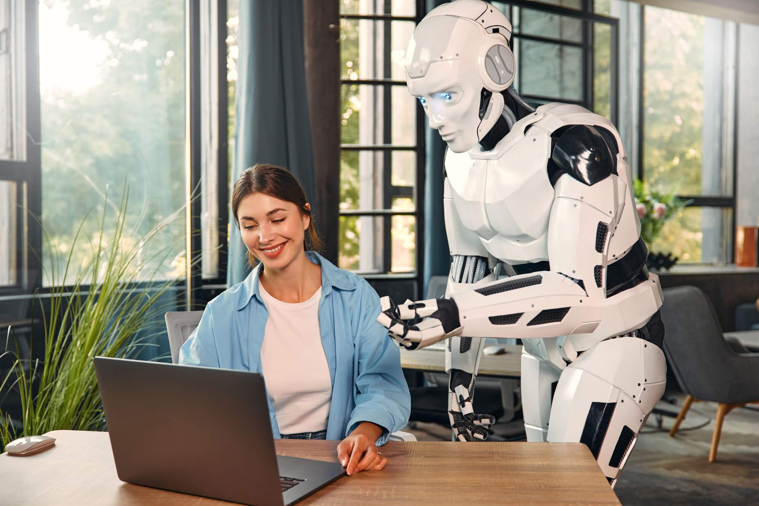 A woman sits at a desk, engaged in conversation with a small robot beside her, showcasing a blend of technology and human interaction