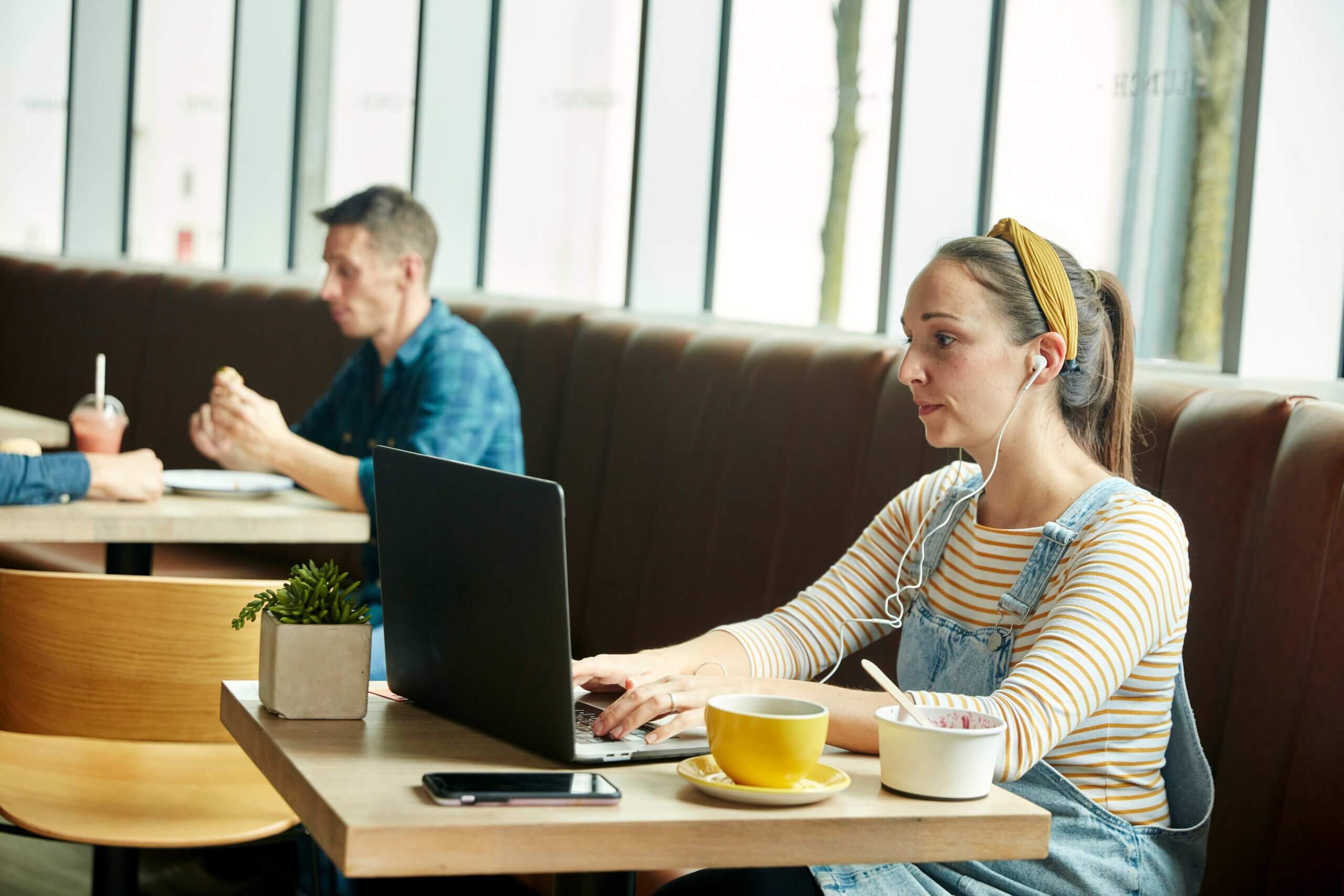 A woman seated at a table, working on a laptop, reflecting on small business trends
