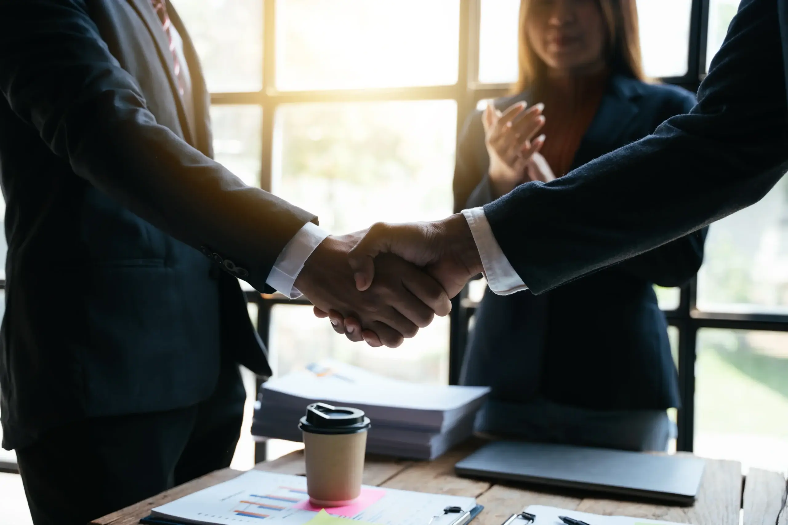 Business partnership handshake sealing deal in bright office environment