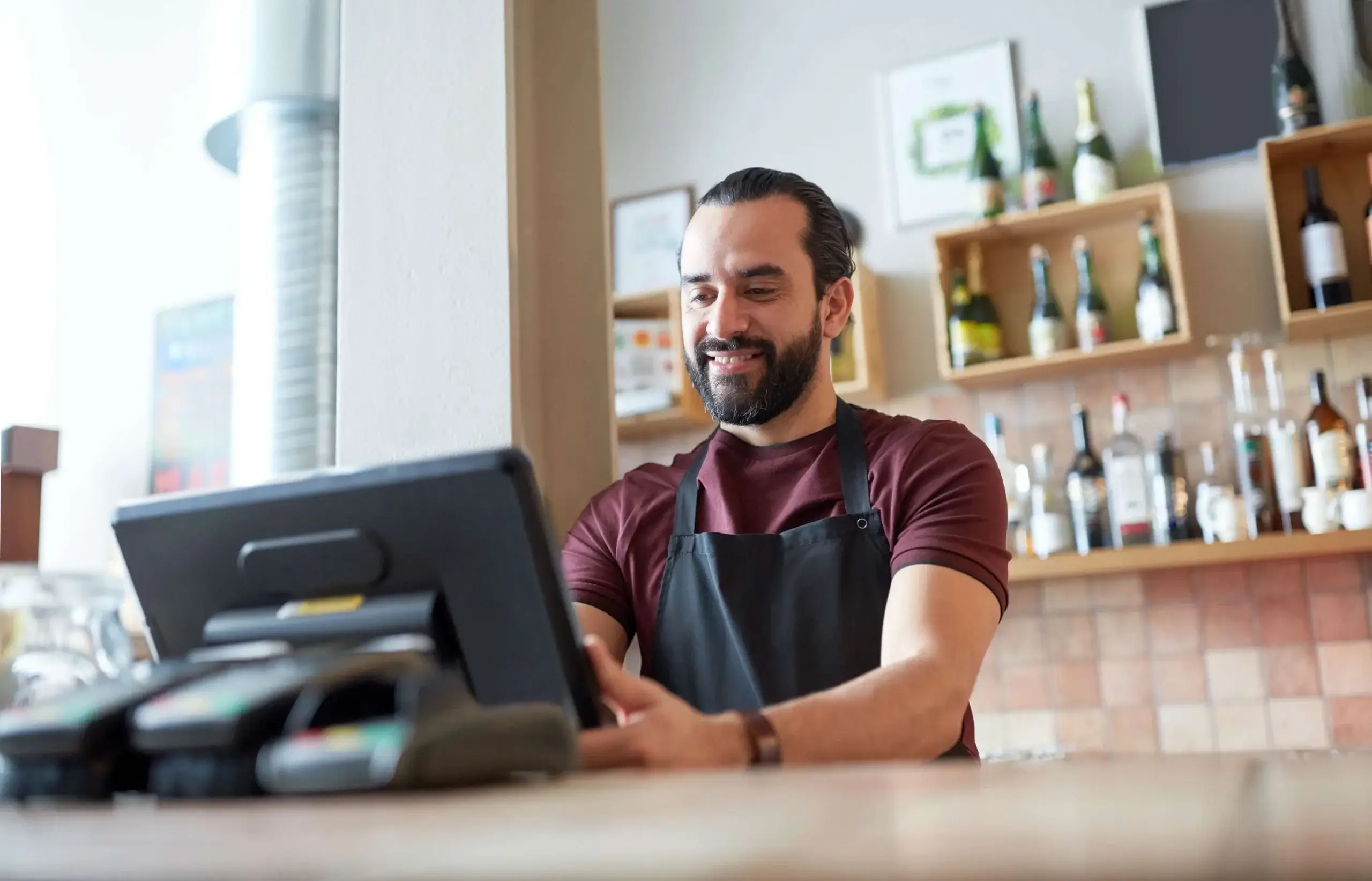 Restaurant staff member using white label POS terminal at bar counter for order processing