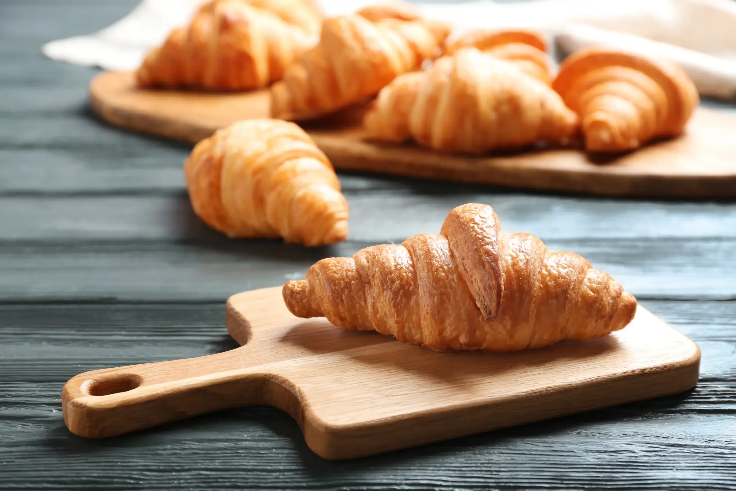 Fresh croissants displayed on wooden board in bakery
